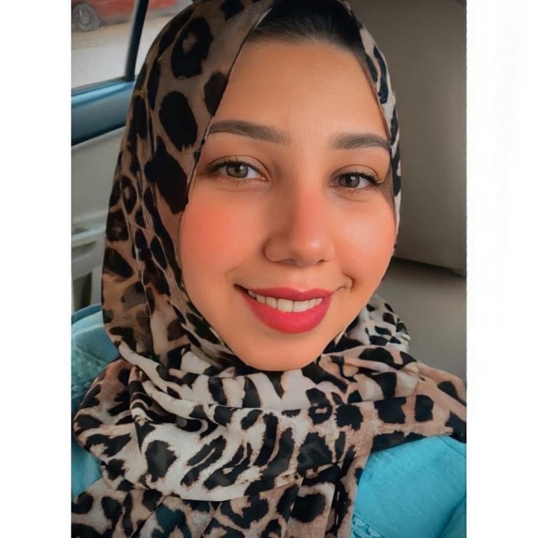 Woman wearing a leopard print hijab and bright pink lipstick, smiling at the camera in an indoor setting